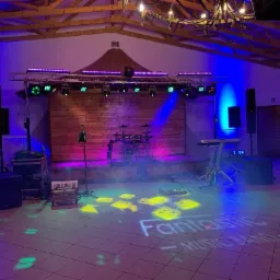 Scena z instrumentami muzycznymi, nagłośnieniem i oświetleniem przygotowana na występ, z projektorem wyświetlającym napis 'Fantastic MUSIC BAND' na podłodze.