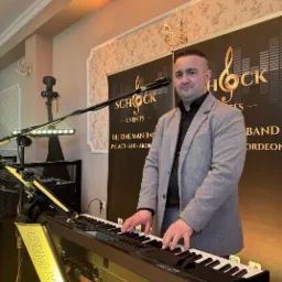 Mężczyzna gra na keyboardzie SD9, na tle baner Schock Events, z oświetleniem scenicznym. DJ, one man band, live act - saksofon i akordeon. Spider Pro.