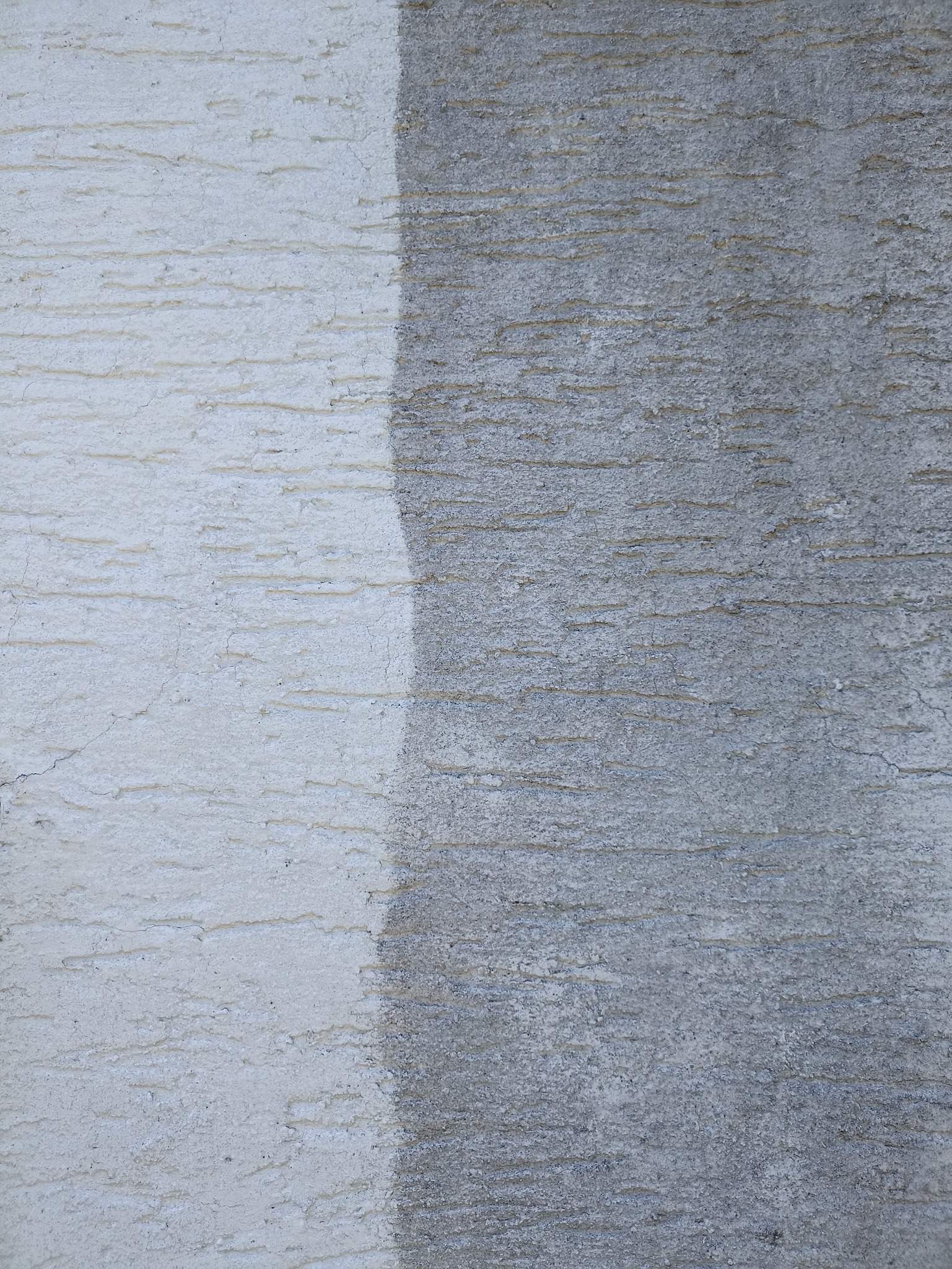 Fragment elewacji z wyraźnym podziałem na część wyczyszczoną i zabrudzoną, ukazujący efekt mycia elewacji.