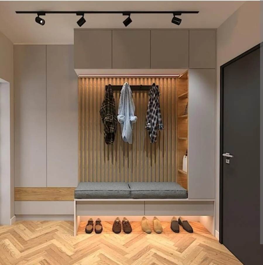 Nowoczesny przedpokój z zabudową meblową: szafy w kolorze szarym, panel z drewnianych listew, siedzisko z szarą poduszką, oświetlenie punktowe sufitowe i podświetlenie LED półki na buty, parkiet...