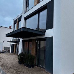 Clean Master 3City Professional cleaning firm - Nowoczesna elewacja budynku w odcieniach bieli i grafitu, z dużymi oknami i minimalistycznym zadaszeniem nad wejściem. W tle widoczne kolejne budynki.