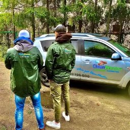 Clean Master 3City Professional cleaning firm - Dwaj pracownicy firmy CleanMaster w zielonych kurtkach stoją przed samochodem z logo firmy na tle zieleni.