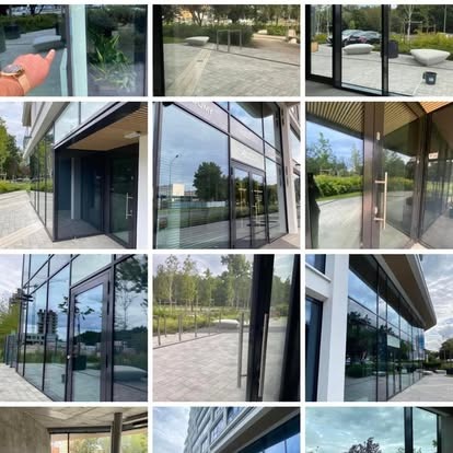 Kompozycja okien budynku w słoneczny dzień. Widoczne odbicia zieleni i błękitnego nieba. Nowoczesna architektura z dużymi przeszkleniami.