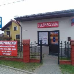 Fasada budynku z szyldem 'Ubezpieczenia', widoczny plakat z godzinami otwarcia i numerem telefonu, logo różnych towarzystw ubezpieczeniowych na drzwiach wejściowych, skrzynka pocztowa.