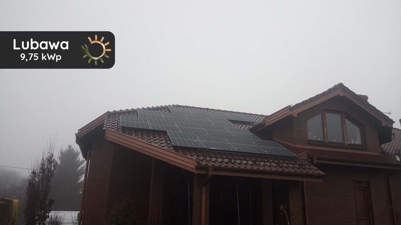 Brązowy dom jednorodzinny z panelami słonecznymi na dachu pokrytym czerwoną dachówką, widoczny w mglisty dzień, z logo firmy w lewym górnym rogu.
