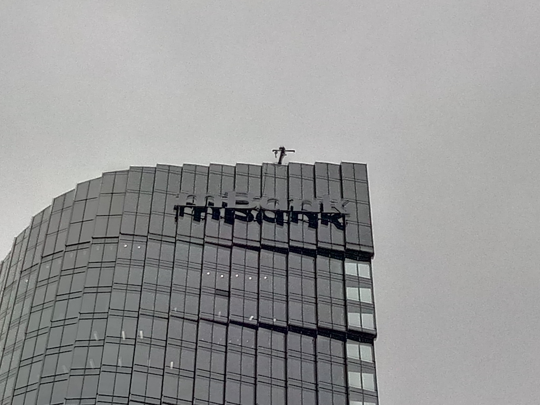 Pracownik na szczycie wieżowca z napisem 'msbank', wykonujący prace na wysokości.