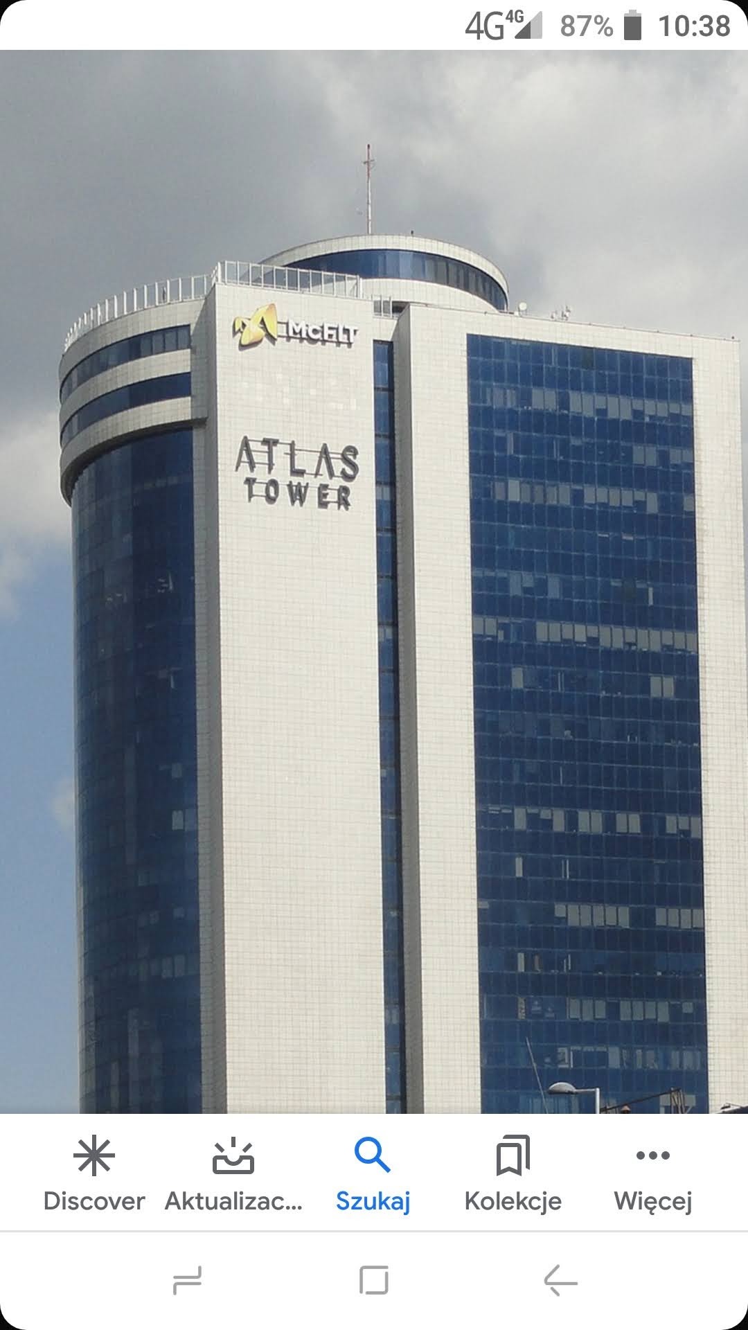 Wysoki budynek biurowy Atlas Tower z widocznym logo AimcelT na tle pochmurnego nieba.
