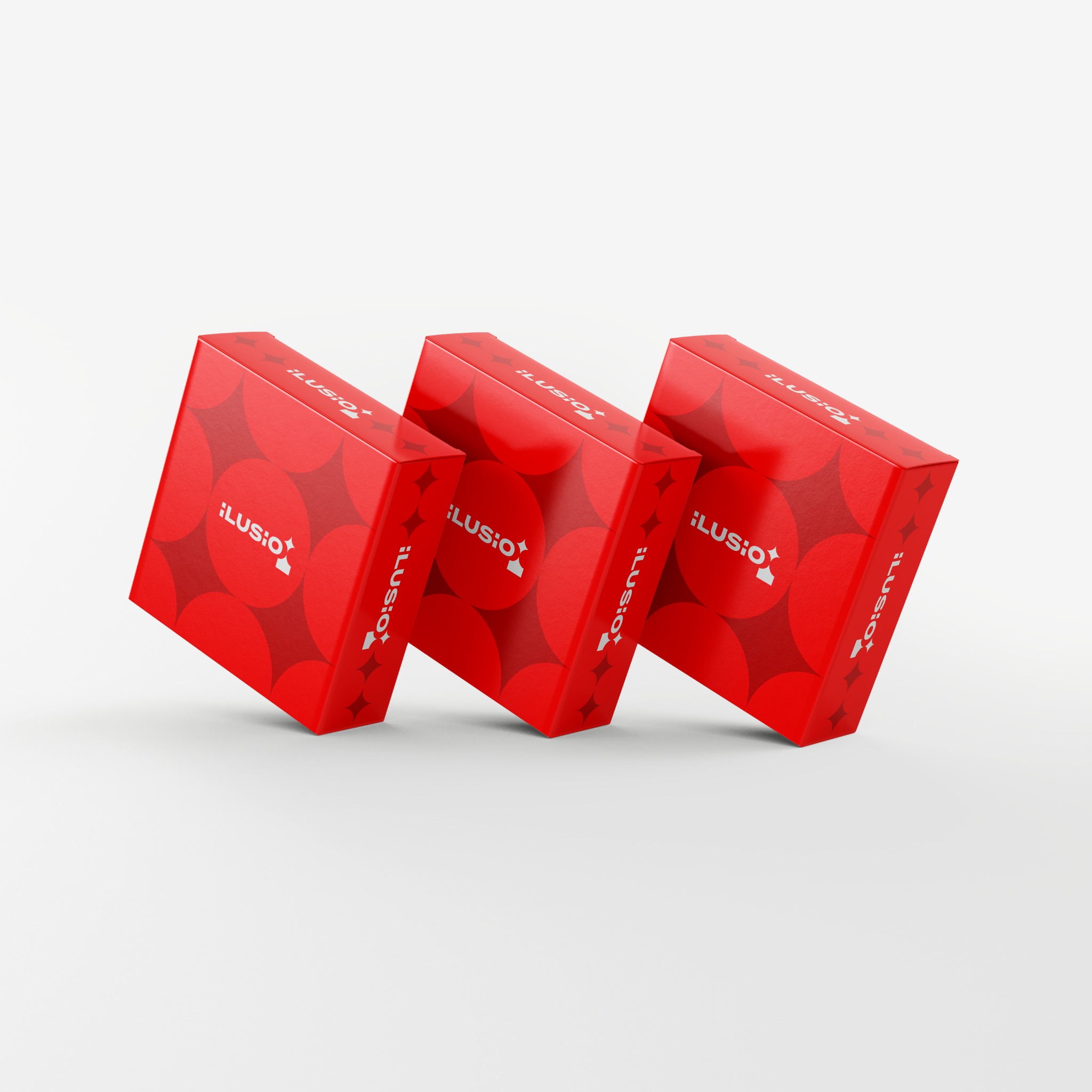 Trzy czerwone, kwadratowe pudełka z logo „iLUSIO” i wzorem z kół i gwiazd, ustawione ukośnie na białym tle, prezentacja produktu.