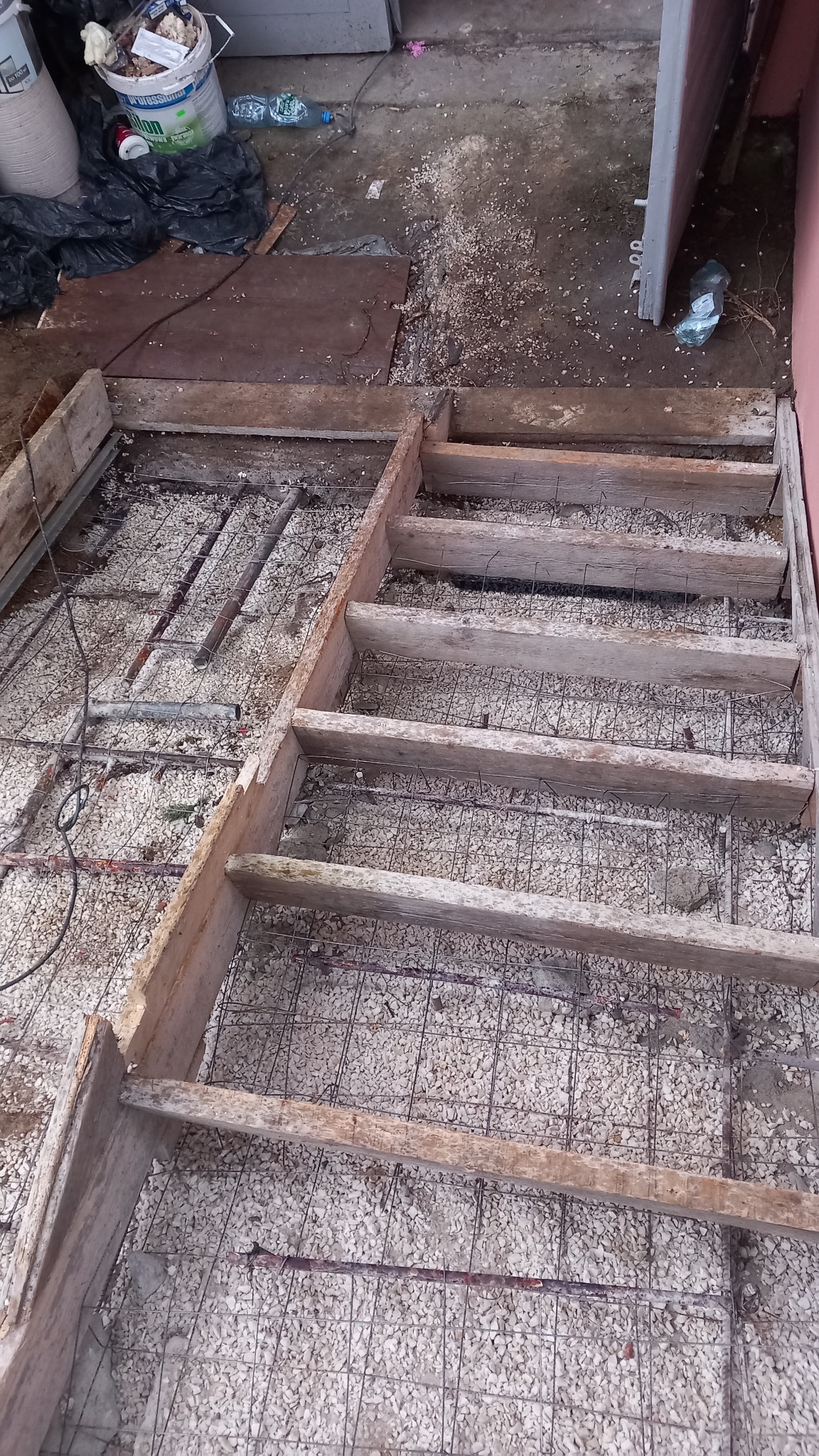 Przygotowanie podłoża pod wylewkę: szalunek z desek, siatka zbrojeniowa i warstwa drobnego kruszywa.