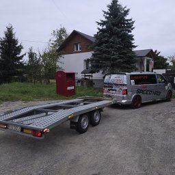 SPEED HADI TAXI MATEUSZ HADAŁA - Szara laweta samochodowa marki BORO, podpięta do szarego busa z reklamami ośrodka wypoczynkowego 'Słoneczny Brzeg' i napisem 'TAXI SPEED HADI', stojąca na żwirowej drodze przed domem.