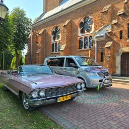 SPEED HADI TAXI MATEUSZ HADAŁA - Różowy Cadillac Cabriolet z żółtymi tablicami rejestracyjnymi RJS 5H oraz srebrny Volkswagen Transporter z grafiką na masce, zaparkowane przed ceglanym budynkiem z ozdobnymi oknami.