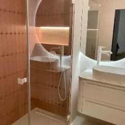 Nowoczesna łazienka we Wrocławiu z kabiną prysznicową z różowymi płytkami i owalną umywalką na białej szafce z podświetlanym okrągłym lustrem.