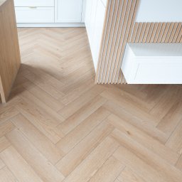 Bel-Pol partner Dekor. Podłogi Drzwi Panele Okna - Jasna podłoga ułożona w jodełkę, fragment białych szafek kuchennych z drewnianymi lamelami na ścianie i wyspa kuchenna z ryflowanym frontem, widok z góry.