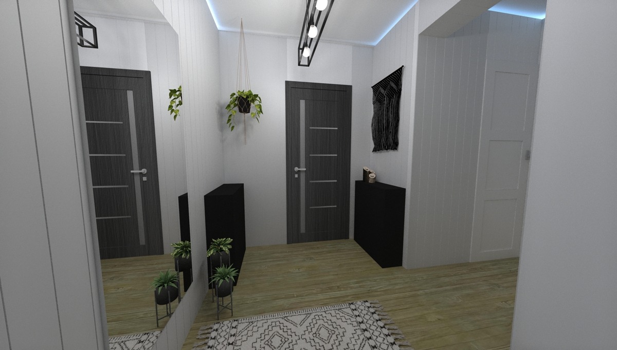 Wnętrze przedpokoju z szarą podwójną ścianą, drewnianą podłogą, czarnymi szafkami i lustrem odbijającym drzwi, dywan w geometryczne wzory.