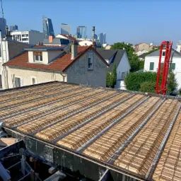 Widok z góry na szalunek stropowy zbrojony siatką stalową, przygotowany do zalania betonem, z widoczną pompą do betonu w tle i zabudową miejską w oddali.