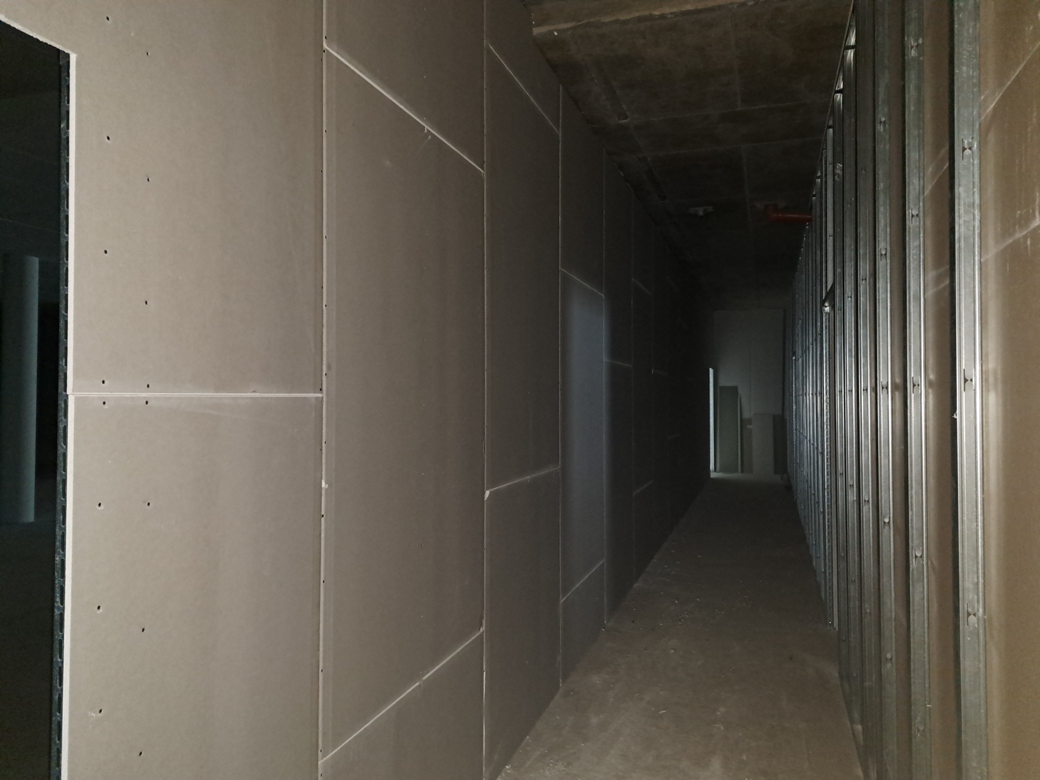 Korytarz w trakcie prac wykończeniowych: szkielet z metalowych profili i płyty gipsowo-kartonowe, widoczne łączenia płyt.
