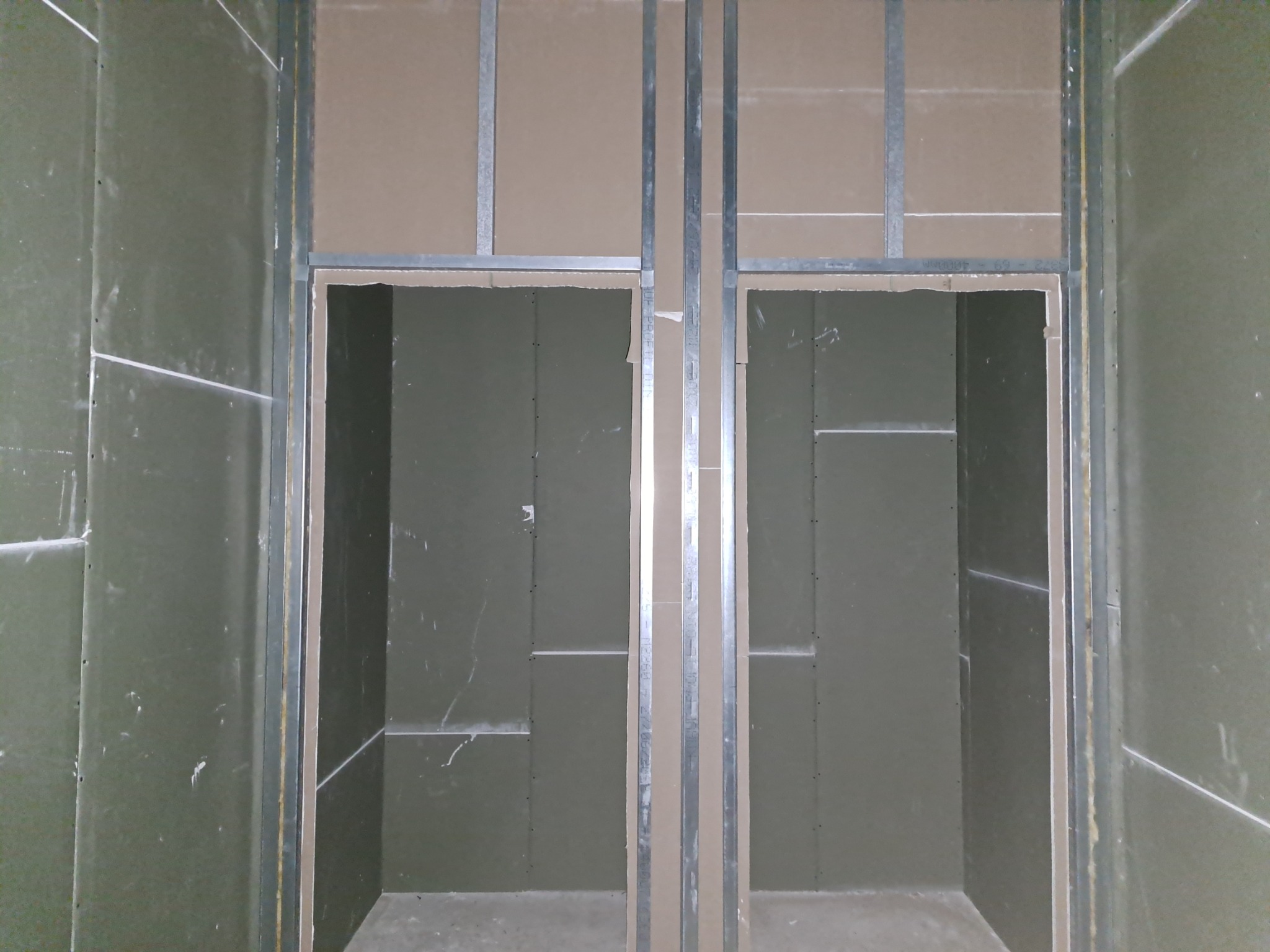 Konstrukcja z profili stalowych i płyt gipsowo-kartonowych tworząca otwory drzwiowe w surowym wnętrzu.