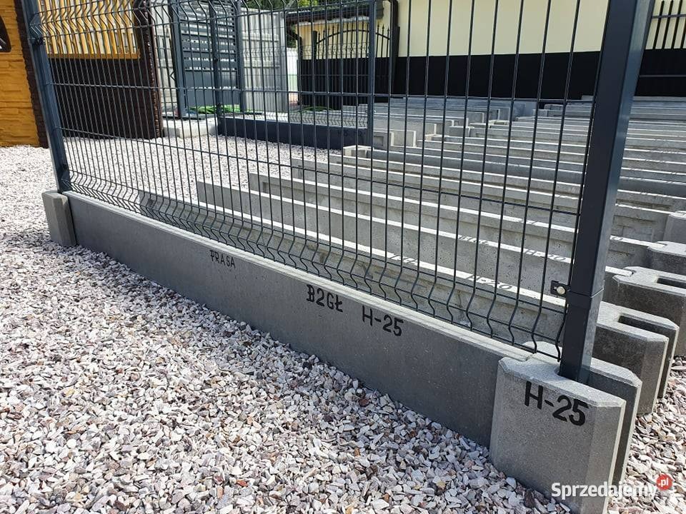 Fragment zainstalowanego ogrodzenia panelowego z podmurówką betonową, widoczne napisy 'PRASA' i 'B2GŁ H-25' na elementach betonowych, podłoże wysypane drobnym kamieniem.
