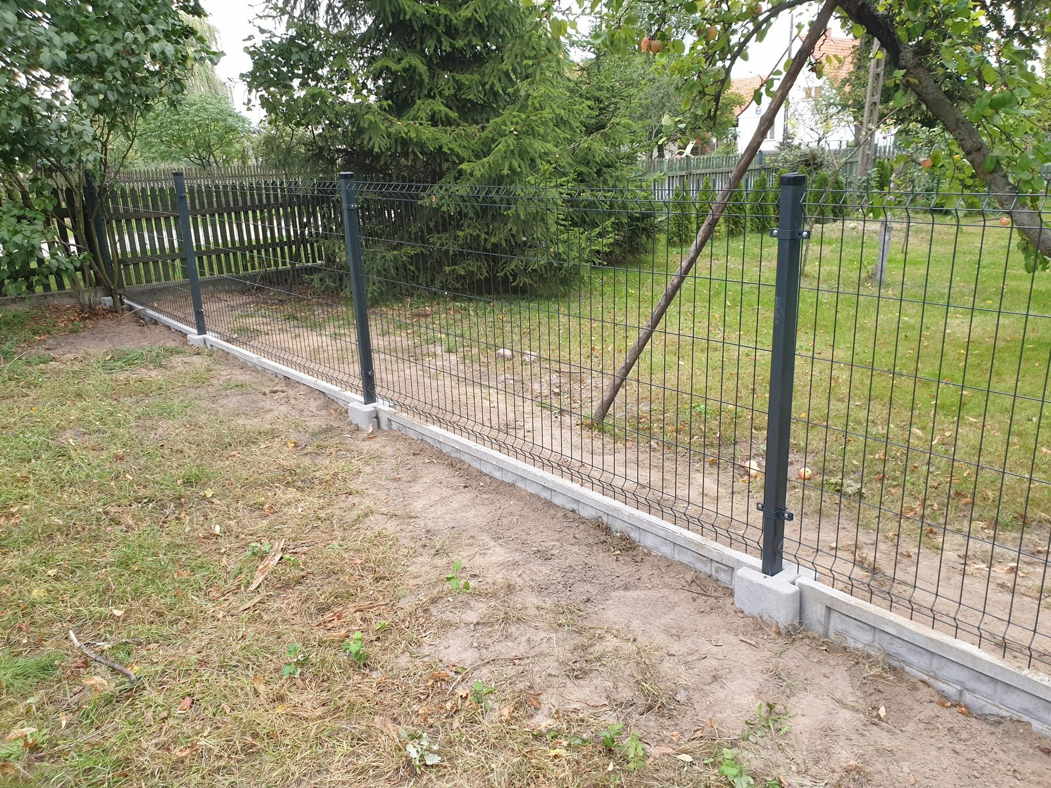 Nowoczesne ogrodzenie panelowe z podmurówką w Gorzowie Wielkopolskim, widok z bliska na szare słupki i siatkę na tle zieleni ogrodu.