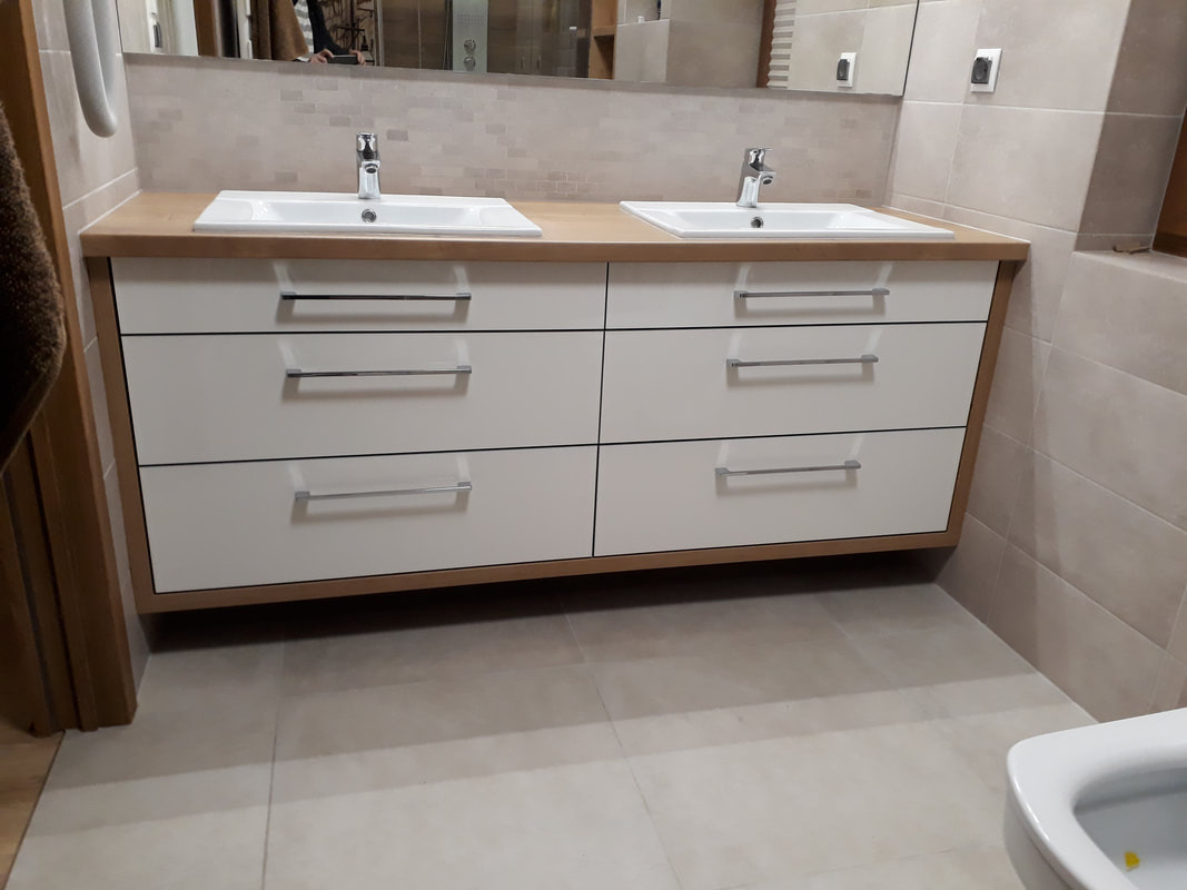 Łazienka z dwiema umywalkami nablatowymi na szafce z białymi frontami szuflad i drewnianym blatem, widok z perspektywy podłogi.