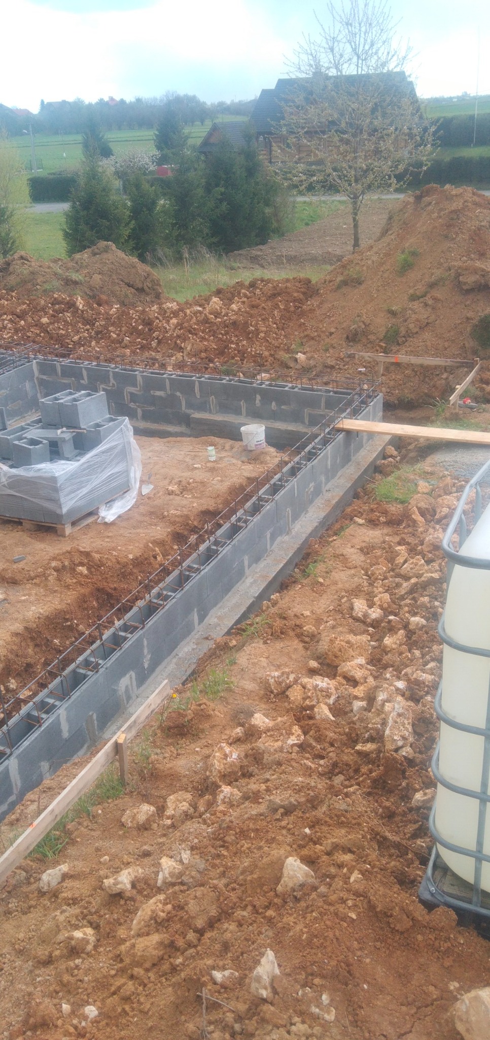 Wykopane fundamenty zbrojone stalą, przygotowane do zalania betonem w Krakowie, na tle krajobrazu z drzewami.