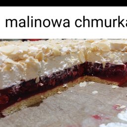 CATERING TRADYCJA PATRYCJA JASIŃSKA - Kawałek ciasta 'Malinowa Chmurka' z biszkoptowym spodem, warstwą galaretki z malinami, bitą śmietaną i płatkami migdałów, na papierze do pieczenia.