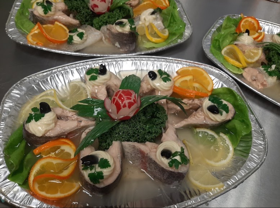 Galaretka z ryby z dekoracjami z cytrusów, warzyw i majonezu na aluminiowych tackach.