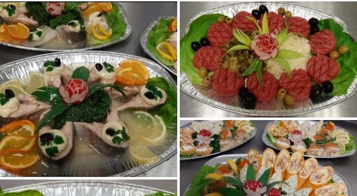 Dekoracyjne, zimne przekąski na aluminiowych tacach: galaretka z rybą ozdobiona cytrusami i oliwkami, pasztet z warzywami, roladki i tartaletki.