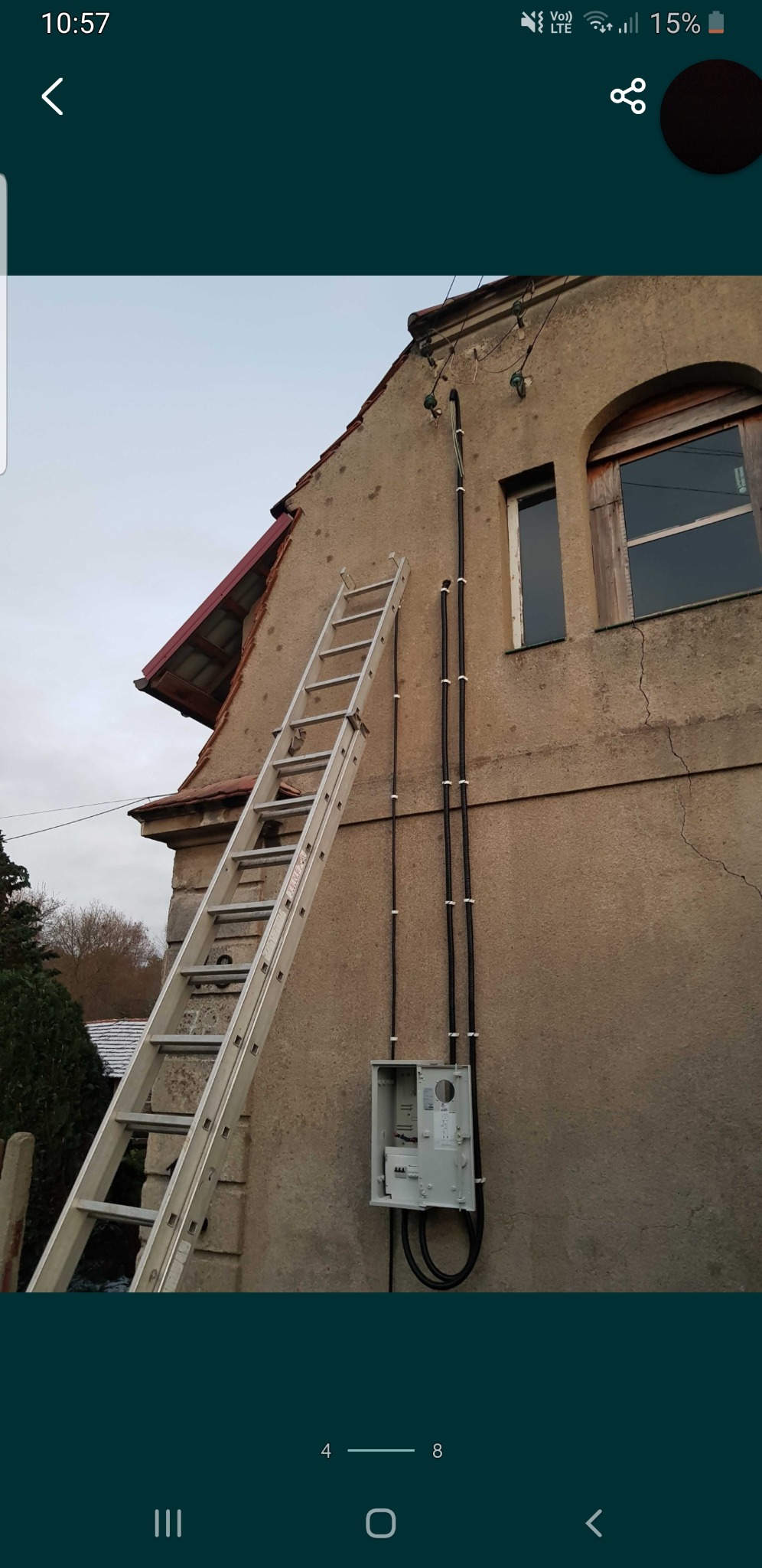 Stara kamienica z widoczną drabiną opartą o ścianę, nowa skrzynka elektryczna i kable w peszlach przymocowane do elewacji.