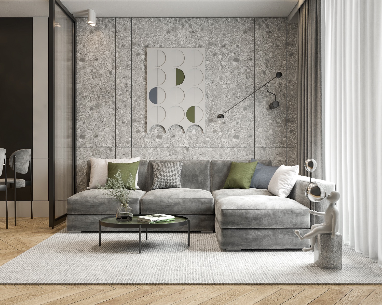 Szary narożnik z zielonymi poduszkami na tle ściany z szarego lastryko i abstrakcyjnym obrazem. Na pierwszym planie stolik kawowy z wazonem i rzeźba siedzącego człowieka dmuchającego bańki.
