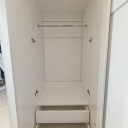 Make Me Woody Konrad Klimiuk - Wnętrze szafy wnękowej z otwartymi drzwiami, widoczne dwie szuflady i drążek na ubrania. Całość w jasnej kolorystyce.