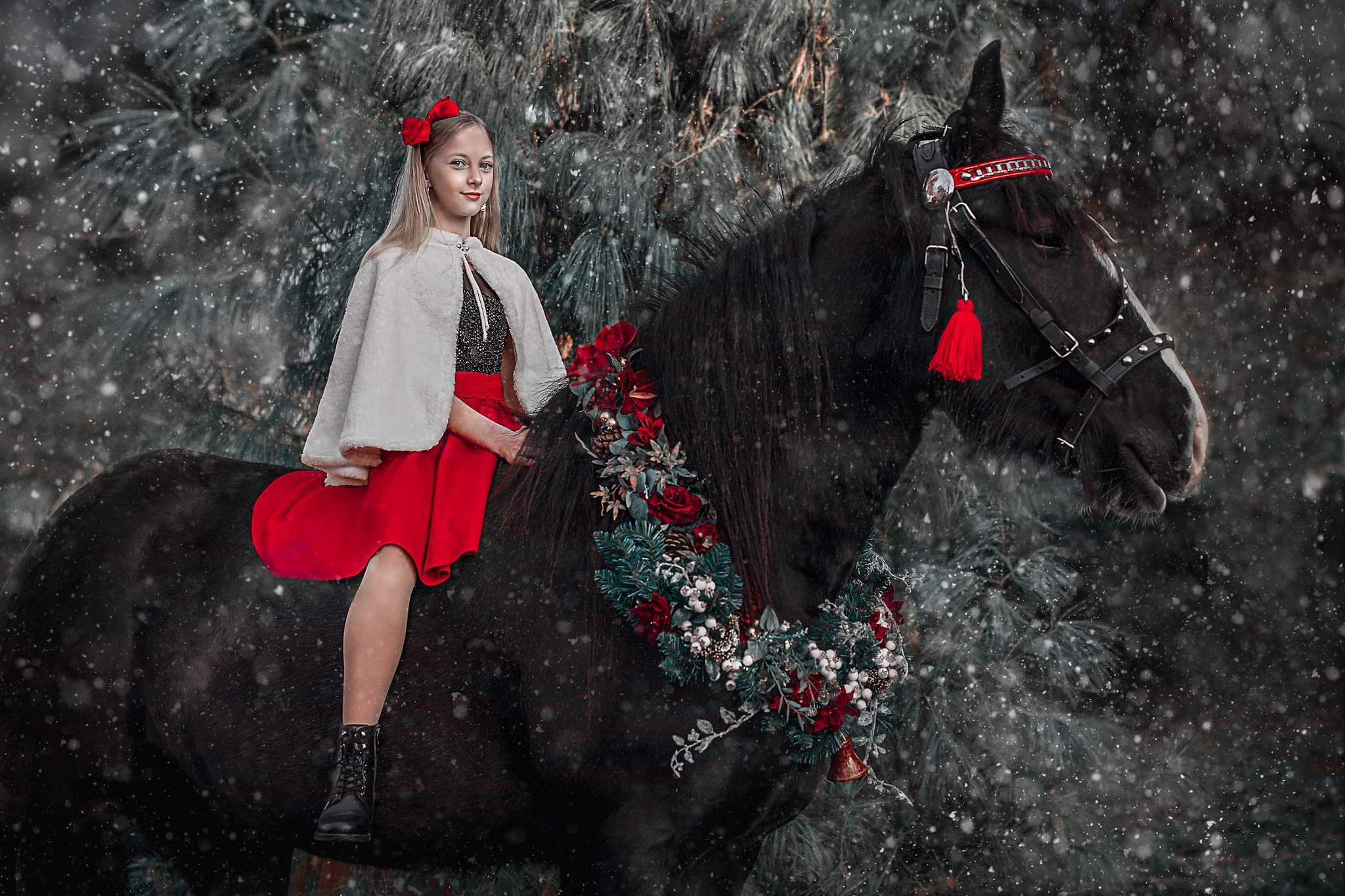 Dziewczyna w czerwonej sukience i białym futerku siedzi na czarnym koniu z dekoracją świąteczną na szyi, w zimowej scenerii z padającym śniegiem.