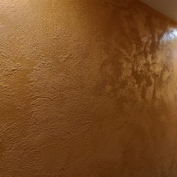 Wall Crafter Remonty ROBERT SIERSZEŃ - Ściana pokryta dekoracyjną farbą w odcieniach złota i brązu, z wyraźną fakturą i połyskującym wykończeniem.