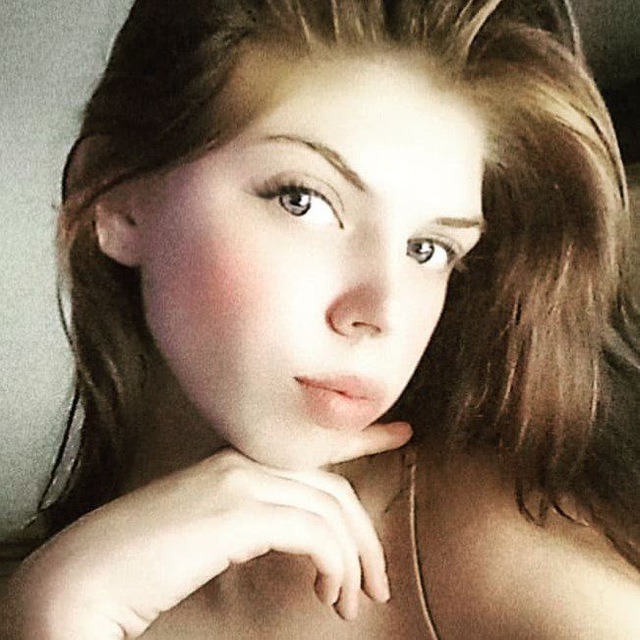 Portret młodej kobiety z ręką pod brodą, delikatny makijaż, naturalne światło.