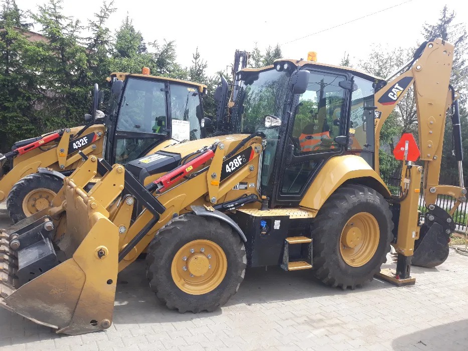 Dwie żółte koparko-ładowarki Caterpillar, modele 428F i 432F, zaparkowane na placu, z widocznymi łyżkami i ramionami kopiącymi.