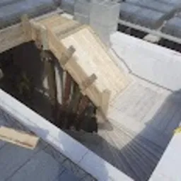 Wykonanie szalunku pod fundament w wykopie, widoczne zbrojenie i bloczki betonowe na obrzeżach.