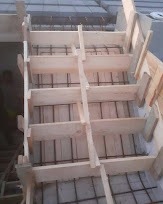 Szczegółowy widok deskowania schodów fundamentowych z widocznym zbrojeniem przed zalaniem betonem, uchwycone pod kątem z góry.