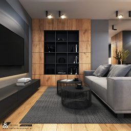 Pro bud - Nowoczesny salon z drewnianą zabudową ściany, czarnymi półkami i stolikami kawowymi oraz szarą sofą i dywanem w jodełkę.