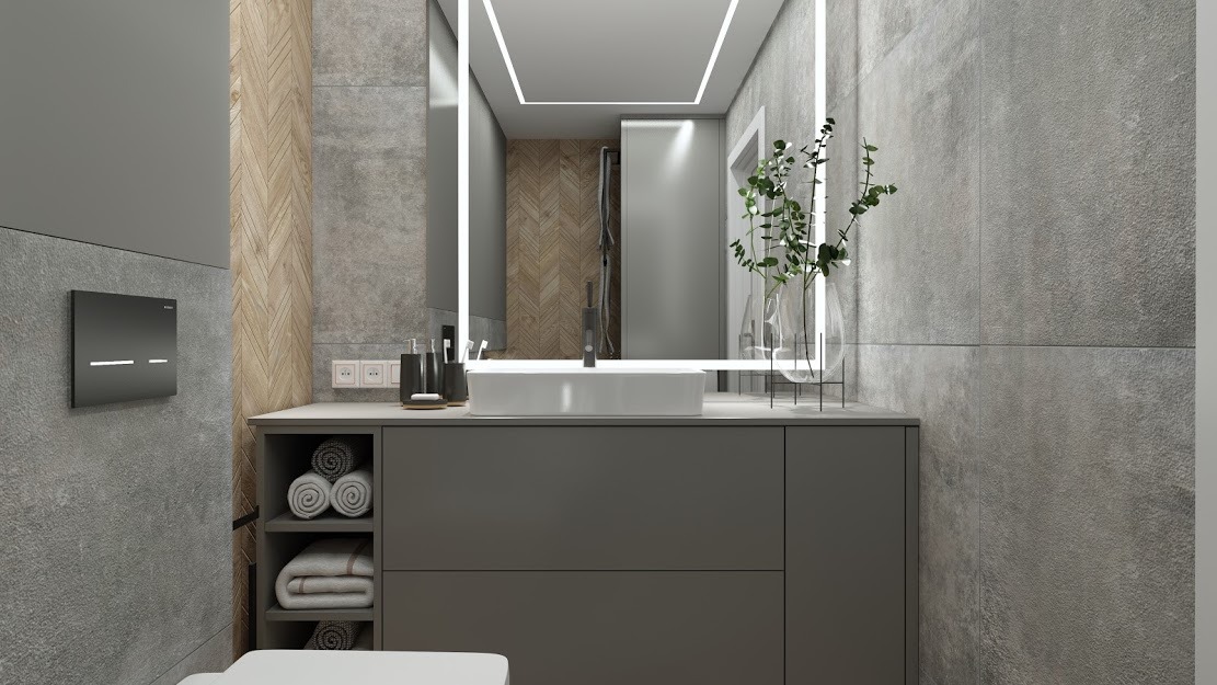 Nowoczesna łazienka z szarą armaturą, podświetlanym lustrem i elementami dekoracyjnymi z drewna jodełkowego oraz ręcznikami w szafce pod umywalką.