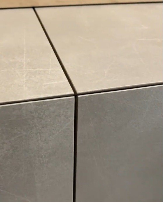 Detale styków płytek ceramicznych w odcieniach szarości i beżu, z widocznymi delikatnymi rysami na powierzchni.