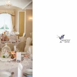 Elegancko nakryty stół weselny z dekoracjami kwiatowymi, klatką dla ptaków i kartami menu, logo firmy Anioły Przyjęć po prawej stronie.