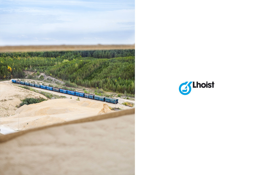 Zdjęcie przedstawia logo firmy Lhoist obok zdjęcia kolejki transportującej surowce mineralne w kopalni odkrywkowej, widzianej z perspektywy podwyższenia.