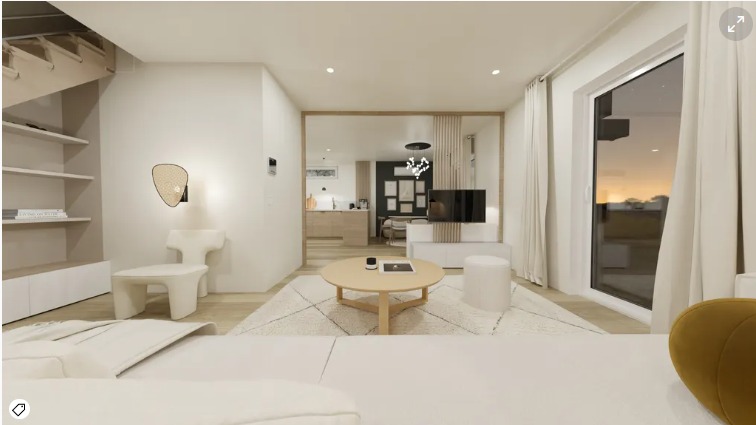 Jasne wnętrze salonu z widokiem na kuchnię i jadalnię, okrągły stolik kawowy na wzorzystym dywanie, designerski fotel i lampa na ścianie, duże okno z widokiem na zachód słońca.