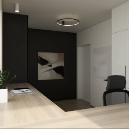 Zielona Posesja - Nowoczesne biuro z drewnianym biurkiem, czarną ścianą z abstrakcyjnym obrazem i minimalistycznym oświetleniem. W tle biała szafa i krzesło biurowe.