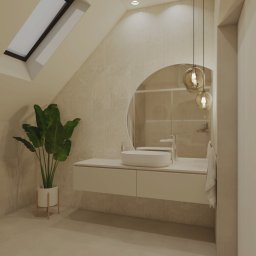 Zielona Posesja - Jasna łazienka na poddaszu z owalnym lustrem, wiszącą szafką z umywalką, rośliną w doniczce i lampami wiszącymi. Widoczne okno dachowe i beżowa kolorystyka.