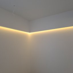 Yevhenii Tolmachov - Wnętrze narożne z podwieszanym sufitem i liniowym oświetleniem LED, widoczne przewody elektryczne wystające z sufitu.