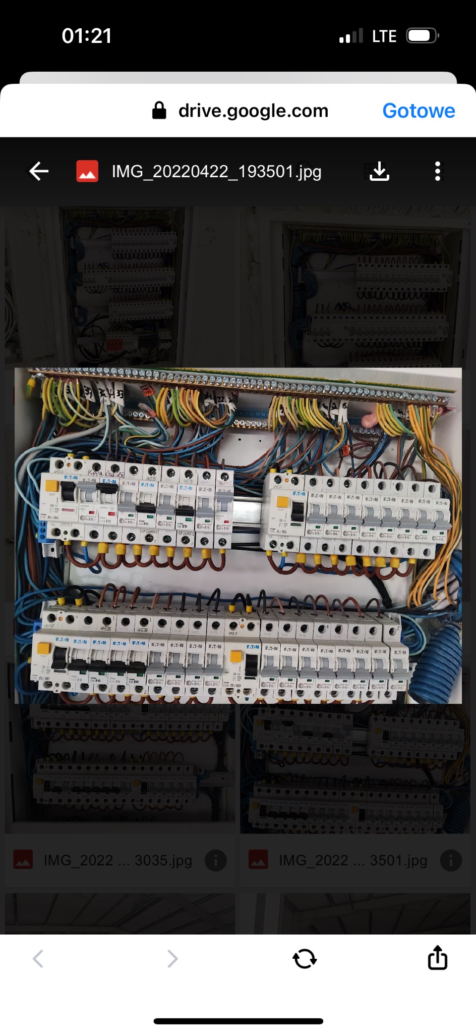 Otwarta skrzynka elektryczna z widocznymi bezpiecznikami EATON, licznymi przewodami w różnych kolorach i listwą zaciskową. Widoczne ślady ręcznego opisu na bezpiecznikach.