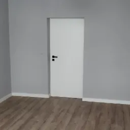 Pokój po remoncie: panele podłogowe w odcieniach brązu, szare ściany, białe listwy przypodłogowe i sufitowe, białe drzwi z czarną klamką oraz nowoczesna biała lampa wisząca.