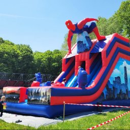 Nadmuchani - Kolorowa konstrukcja rekreacyjna ze Spidermanem w Wodzisławiu Śląskim. Dzieci bawią się na tle zieleni i błękitnego nieba. Atrakcja na imprezę plenerową.
