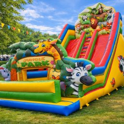 Nadmuchani - Kolorowy, dmuchany zamek ze zjeżdżalnią w stylu dżungli, z motywami zwierząt i napisem 'Jungle Park', ustawiony na trawie, idealny na imprezy plenerowe.